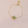 Macro view of gold adjustable bracelet with green gemstone flower and box chain - Green