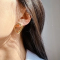 Vue détaillée d'un mannequin portant des boucles d'oreilles dorées torsadées minimalistes - Doré