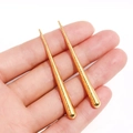 Boucles d'oreilles pendantes dorées à texture métallique présentées sur la main - Or