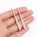 Longues boucles d'oreilles argentées texturées en forme de goutte tenues dans la main - Argent