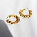 Orecchini a cerchio dorati a C con trama martellata irregolare su sfondo bianco - Oro