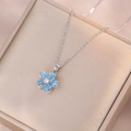 Détail du pendentif fleur en opale bleue rotative avec zircon sur chaîne argentée - Collier fleur bleue rotative argentée