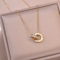 Detail of rose gold double interlocking rings necklace with Roman numerals and zircons - Gold