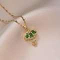 Pendentif parapluie doré élégant avec zircons verts sur un tissu en satin rose - Collier Parapluie Vert Émeraude