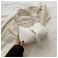 Detail of white leather underarm bag featuring a gold metal hook and minimalist fringe charm - White