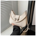 Detalle del bolso de media luna crema con lazo plateado y asa de cadena decorativa - Blanco