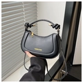 Detail of a black crescent handbag featuring knotted handle and gold metal accents - Black