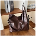 Detail view of a large brown PU leather tote bag with dual stitching on a bookshelf - Brown