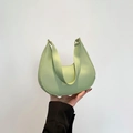 Minimalist mint green crescent shoulder bag in smooth PU leather held by hand - Green