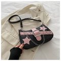 Close-up of black denim shoulder bag featuring pink leather stars and silver buckle - Black