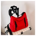 Versatile red nylon crossbody bag with black zipper on a white striped suitcase - Red