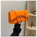 Macro detail of vibrant orange shoulder bag featuring silver buckle and accordion side gussets - Orange