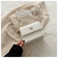 Detail of white PU crossbody bag featuring a gold butterfly buckle on beige blazer - White