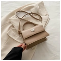 Detail of khaki PU leather bag with white butterfly relief on beige blazer backdrop - Khaki