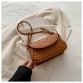 Detailed view of the caramel brown heart-quilted leather underarm bag on a beige blazer - Brown