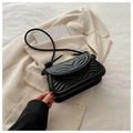 Detail of black quilted shoulder bag with heart and V-shaped patterns on leather surface - Black