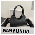 Detail of black PU leather handbag with gold hardware and curved opening on white box - Black
