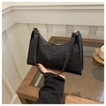 Detail einer schwarzen Pailletten-Baguette-Tasche mit Glitzertextur und Goldreißverschluss - Schwarz