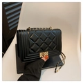 Klassische schwarze Stepptasche mit goldener Kette auf einem weißen Stuhlhintergrund - Schwarz