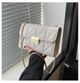 Detalle de bolso acolchado beige con textura en V y cierre de hebilla metálica dorada - Blanco Roto