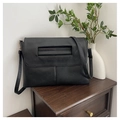 Close-up of black lychee grain PU leather crossbody bag with a decorative handle on the front - Black