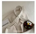 Détail du sac bandoulière en similicuir crème avec large sangle et charm en peluche - Blanc avec Pendentif