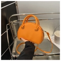Detail view of the orange semi-circular leather handbag on a modern silver metal shelf - Orange