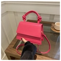Détail d'un sac à main rose en similicuir avec motif crocodile et poignée nouée - rose vif