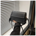 Detailopname van een minimalistische zwarte crossbodytas met rechthoekig reliëfdetail - Zwart