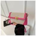 Dettaglio di una borsa a tracolla in paglia con finiture in pelle rosa e fibbia oro - rosa acceso