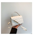 Detail of white quilted handbag showing geometric triangular texture and gold metal clasp - White