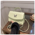 Détail d'un sac à main matelassé vert clair avec fermoir papillon argenté sur table en bois - Vert