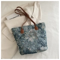 Close-up of floral tapestry fabric and leather handles on a large tote bag - Blue