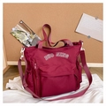 Détail du sac fourre-tout en toile bordeaux avec lettrage blanc et bandoulière réglable - Rouge