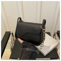 Close-up of black crossbody bag featuring wavy flap and gold ring chain detail - Black