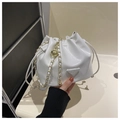 Détail du sac seau blanc à cordon avec chaîne dorée et plaque triangulaire en métal - Blanc