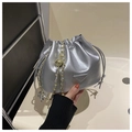 Gros plan du sac seau argenté avec texture cuir, bandoulière chaîne et logo triangle - Argenté