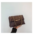Close-up of dark brown quilted leather surface with elegant gold metal buckle and chain - Brown