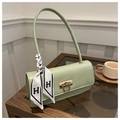 Dettaglio borsa quadrata in pelle verde salvia con nastro di seta stampato H su legno - Verde