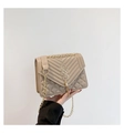 Detail of beige quilted crossbody bag featuring gold tassel and V-stitch pattern - Khaki