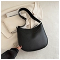 Detail of black lychee grain leather crescent bag placed on a cream blazer - Black