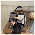 Close-up of black and white plaid handbag with a metallic twist lock and top handle - Gray