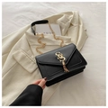 Detail of black faux leather crossbody bag featuring gold logo and elegant tassel charm - Black