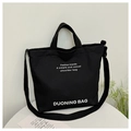 Minimalist black canvas tote bag with shoulder strap and white printed lettering - Black