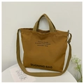 Close-up of brown canvas tote with dual handles, shoulder strap and slogan print - Brown