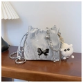 Silver bucket bag with butterfly hardware and plush monster charm in a home setting - With Pendant Style / Silver