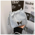 Fashionable light blue bucket bag with metallic bow and woven chain strap held by model - Basic Style / Silver