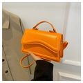 Close-up of bright orange square crossbody bag with unique wave pattern texture - Orange