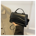 Detail van zwarte crossbodytas met golfvormige flap, goudkleurig handvat en leer - Zwart