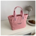 Rosafarbene Canvas-Eimertasche mit schwarzem Schriftzug und Metallnietendetails - Rosa